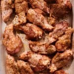 Raw chicken wings coated in a mix of spices and herbs, arranged on a parchment-lined baking sheet, ready to be transformed into delicious oven-baked wings.