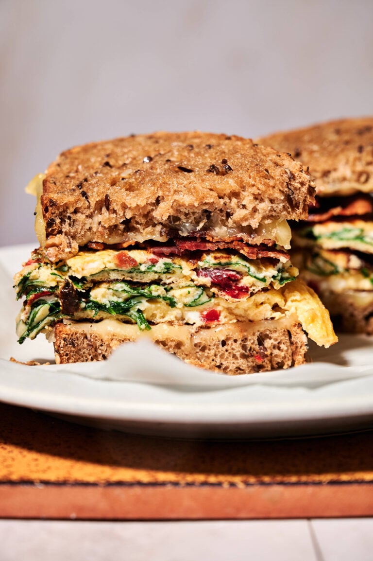 Layers of cooked bacon, omelet and melted cheese on the prepared toast.