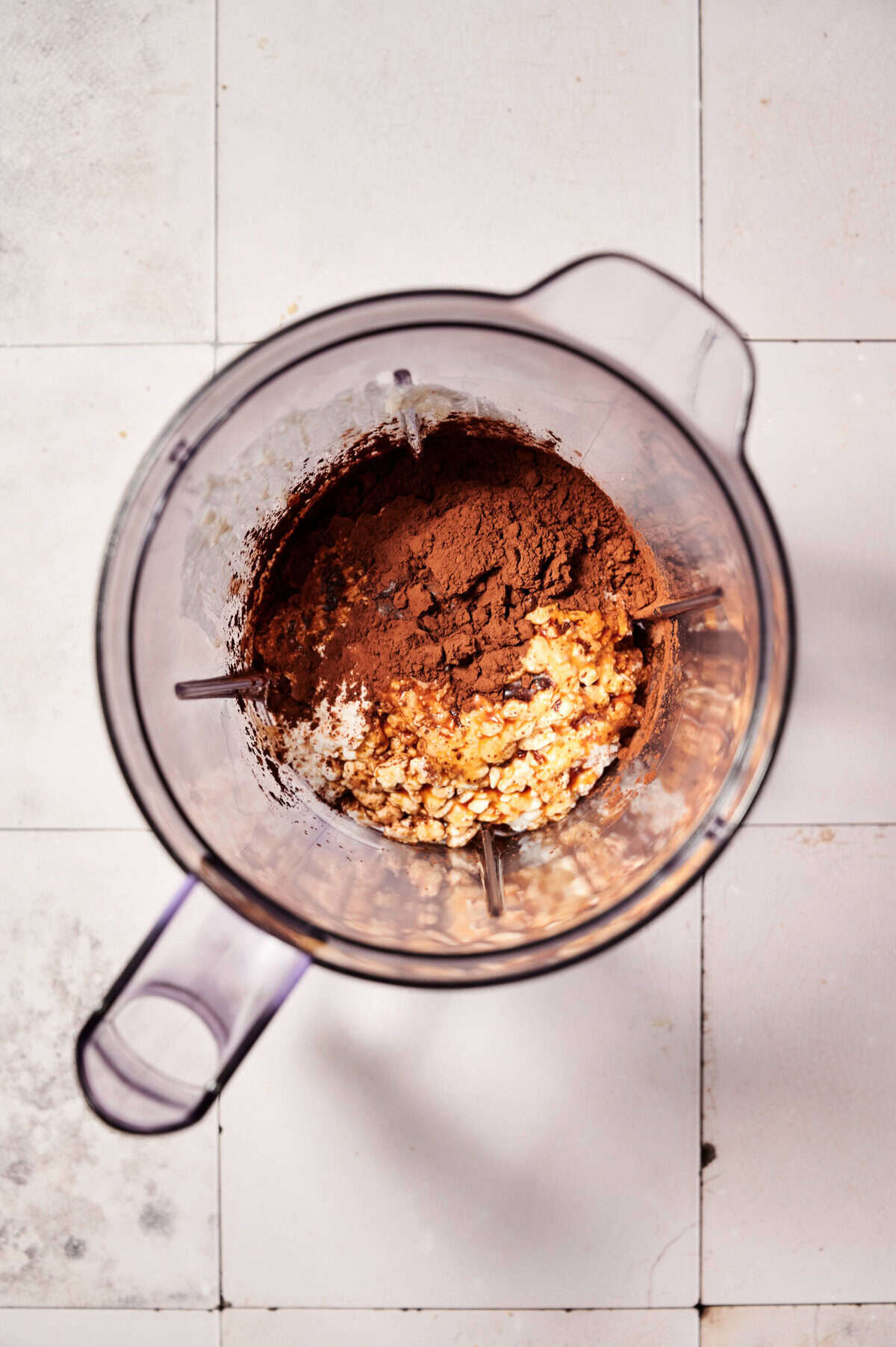High protein chocolate mousse ingredients in a blender: cottage cheese, cocoa powder, and sweetener ready to be blended for a healthy dessert.