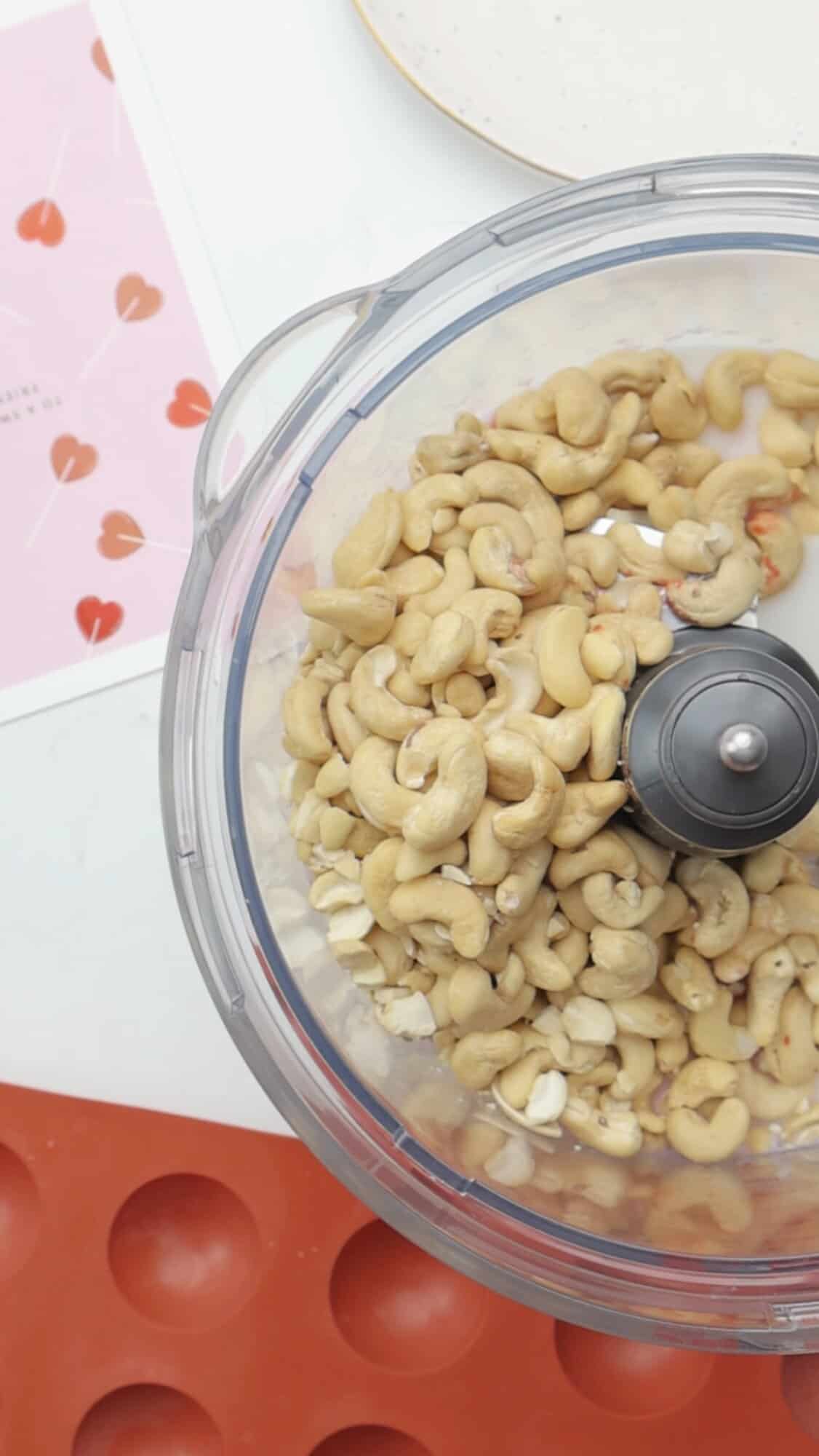 Soaked cashews in a food processor bowl ready to blend for healthy raspberry cocoa truffles.
