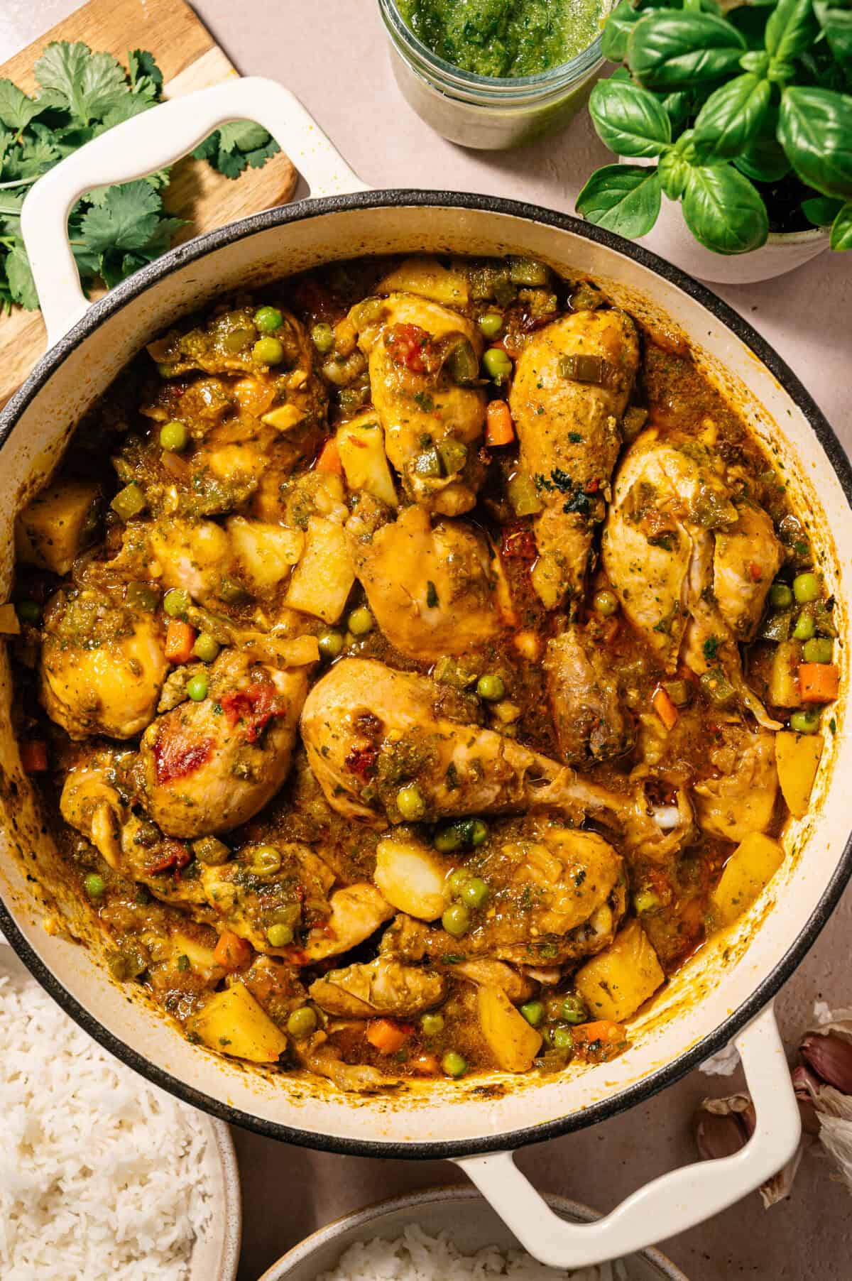 Dutch oven filled with simmered seco de pollo ecuatoriano chicken stew with potatoes, peas, and carrots ready to serve with rice.