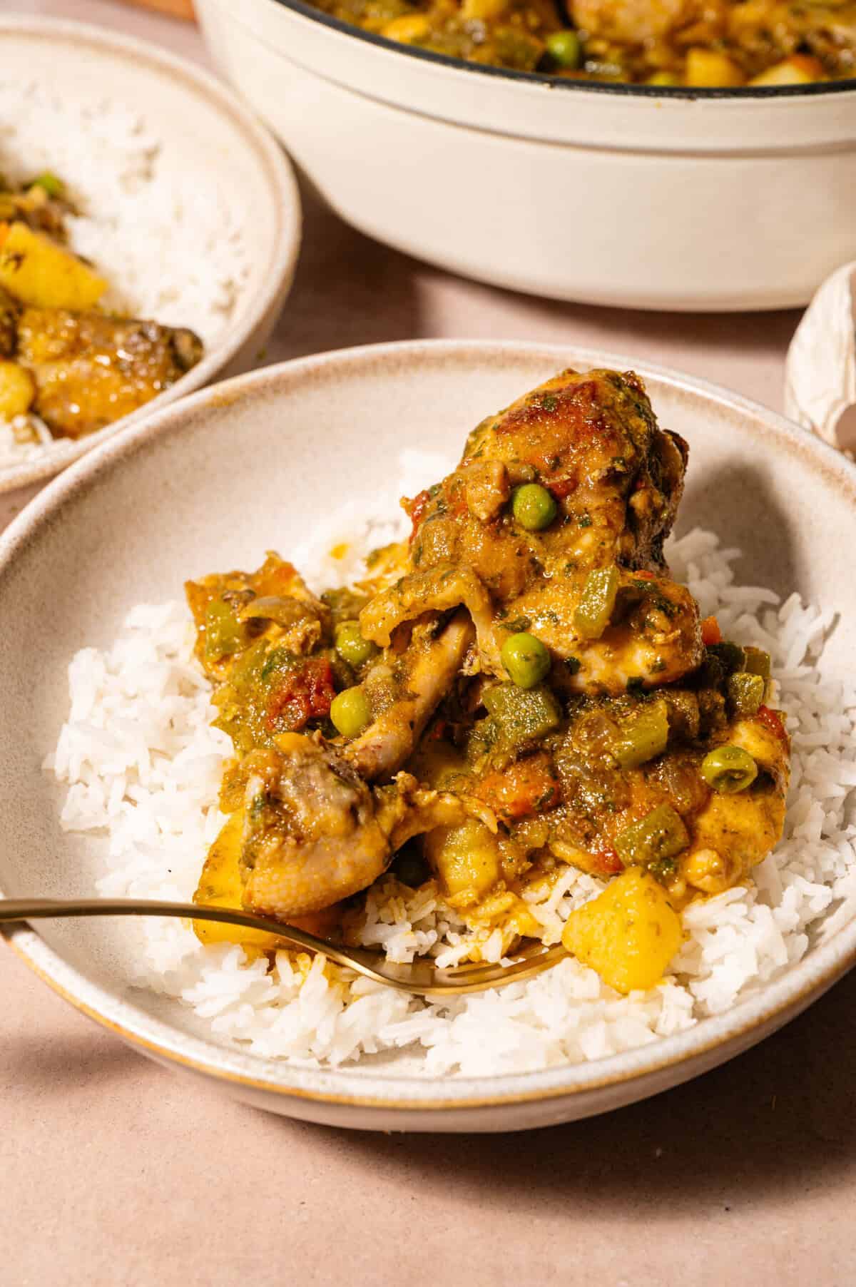 Bowl of seco de pollo ecuatoriano chicken stew with peas, carrots, and potatoes served over fluffy white rice.