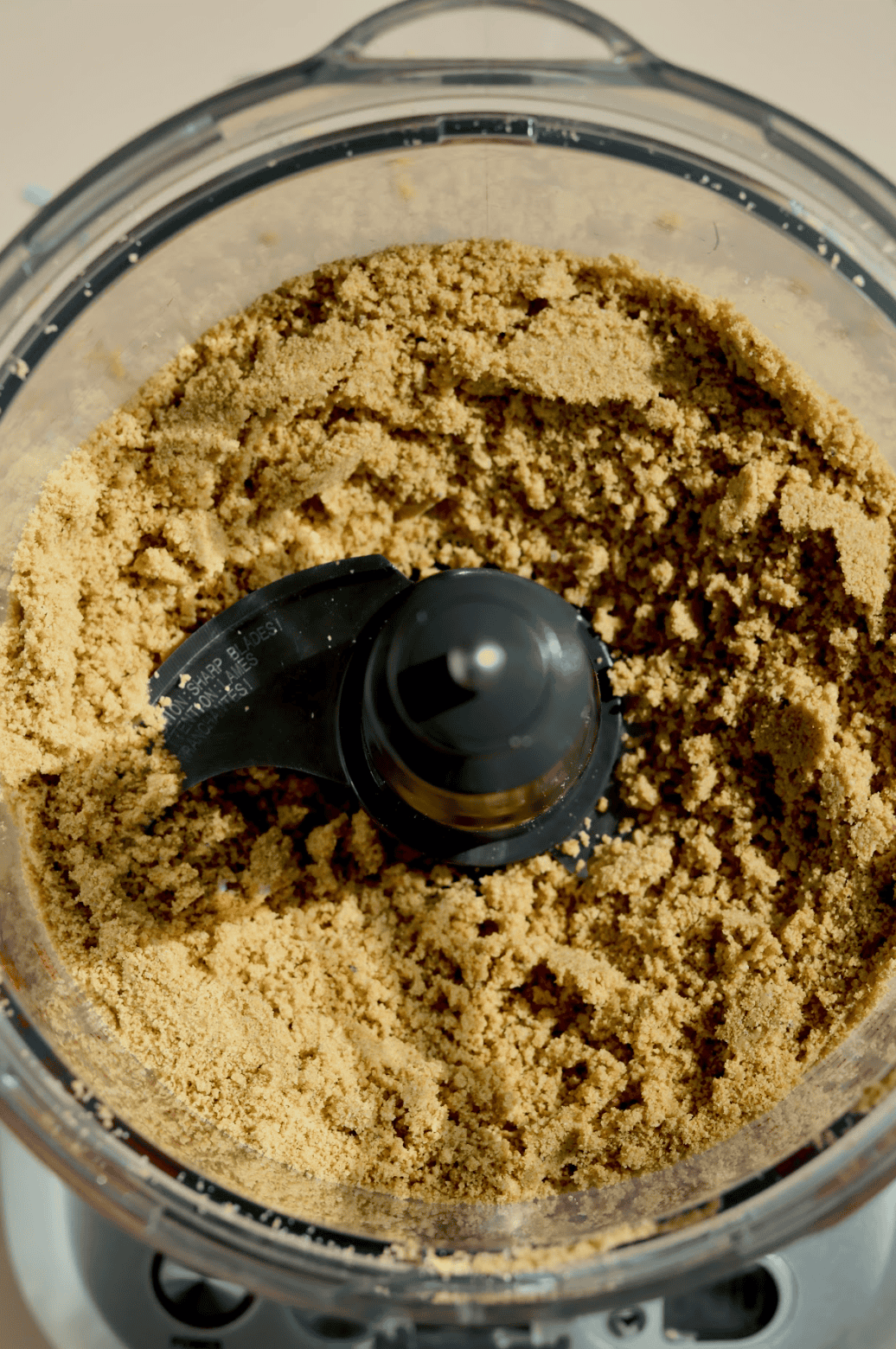 A glass bowl contains brown sugar pressed to one side, white liquid (likely milk or cream), and a splash of vanilla extract—perfect beginnings for no-bake dessert favorites like birthday cake truffles. Sprinkles decorate the surrounding surface.