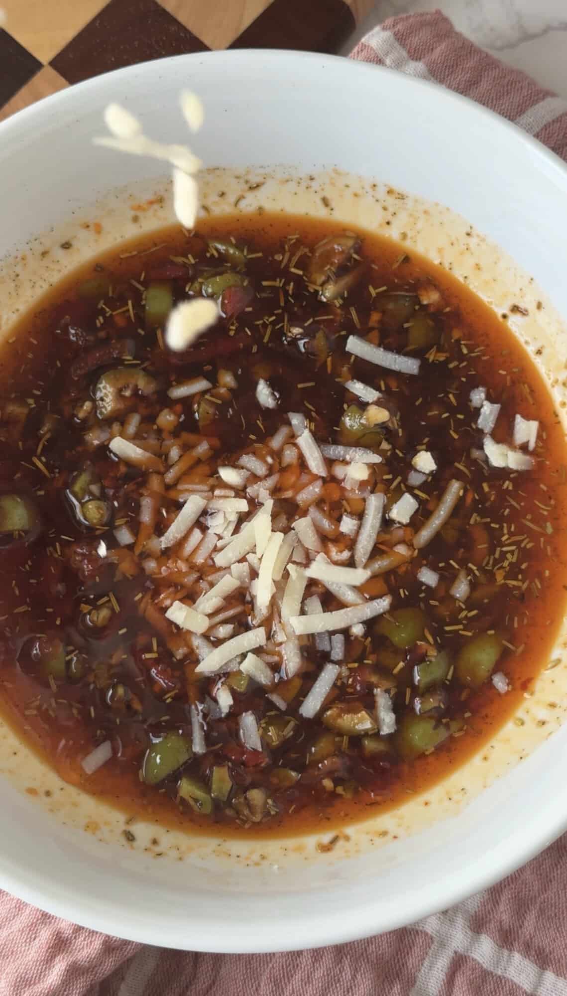 Sprinkling shredded Parmesan over Italian herb brea