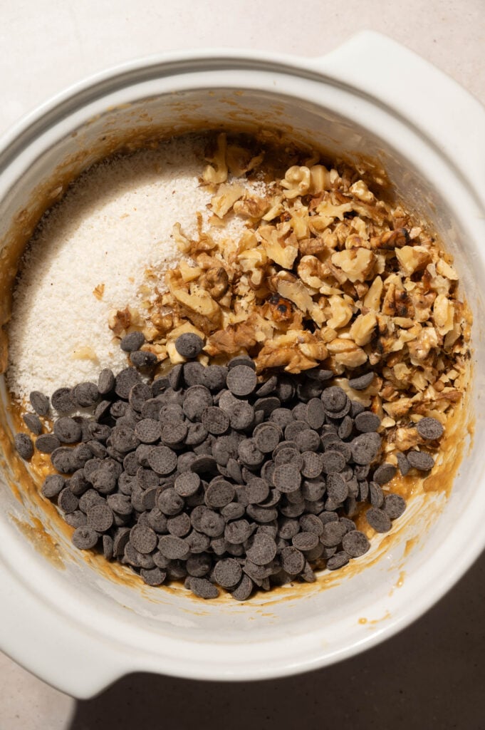 Chocolate chips, shredded coconut, and chopped walnuts added to oatmeal cookie dough