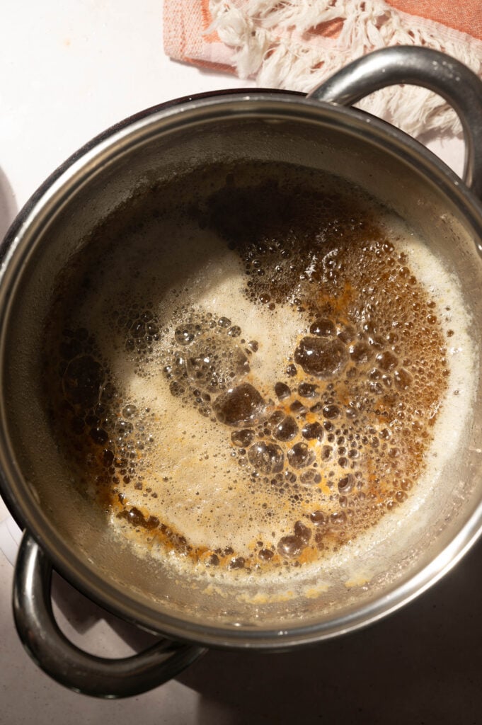 Browned butter foaming in a saucepan with golden brown milk solids
