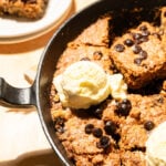 Cast iron skillet cookie with vanilla ice cream and a slice on a plate