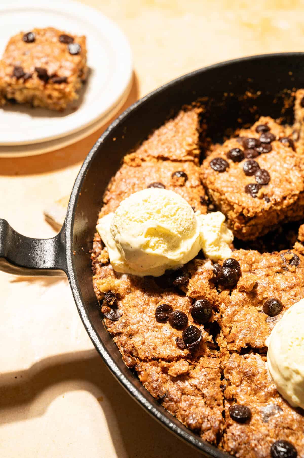 Cast iron skillet cookie with vanilla ice cream and a slice on a plate