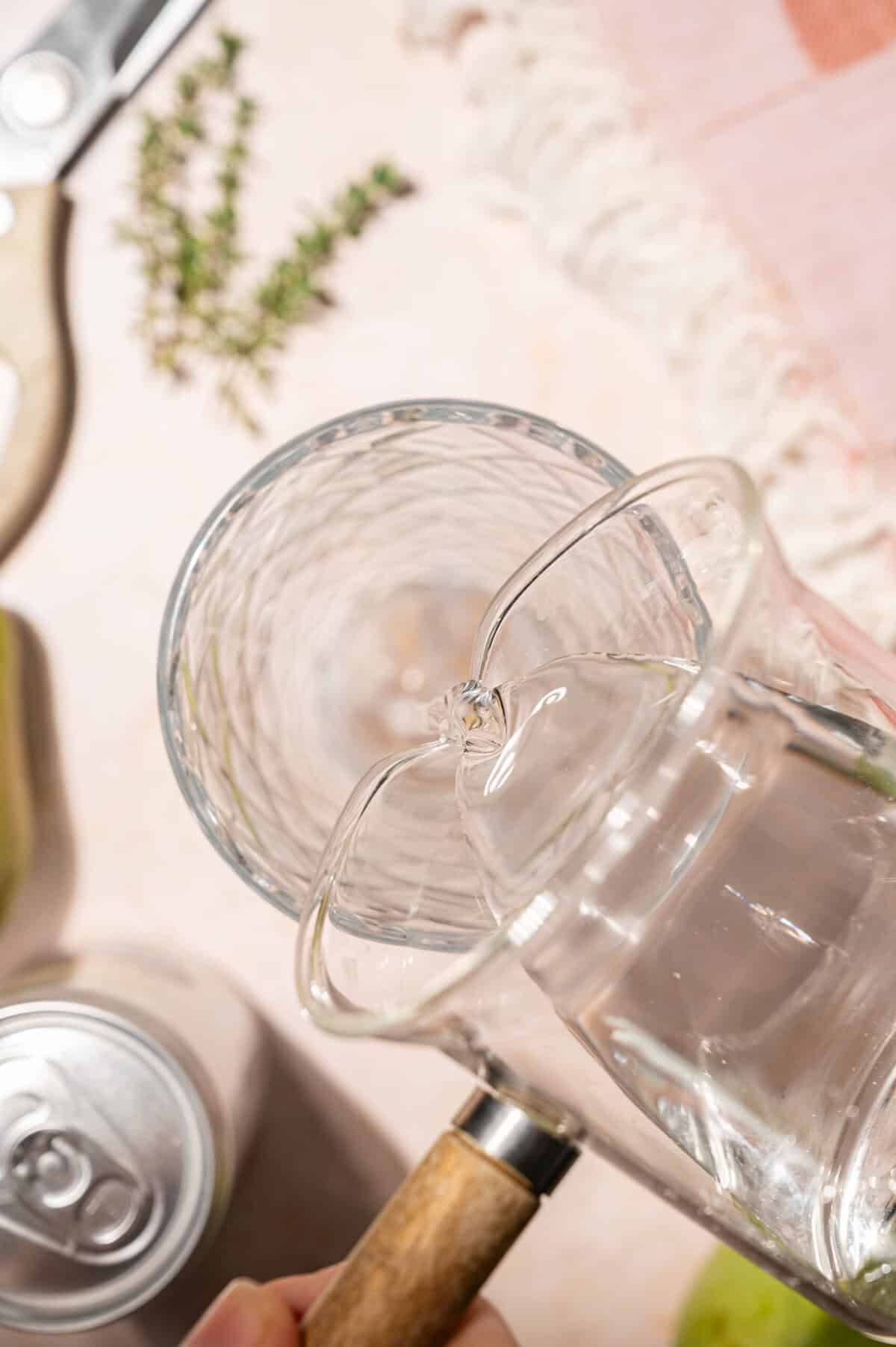 Pouring vodka into a cocktail shaker to make a pear vodka cocktail