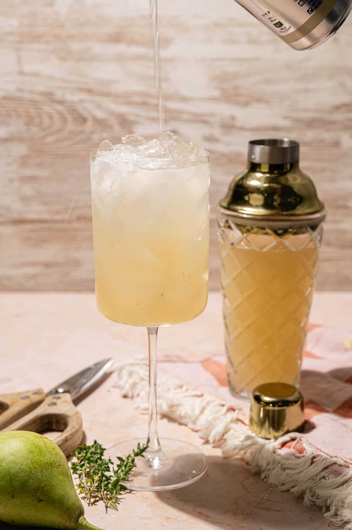 Topping a pear vodka cocktail with soda water to make a Pear Collins