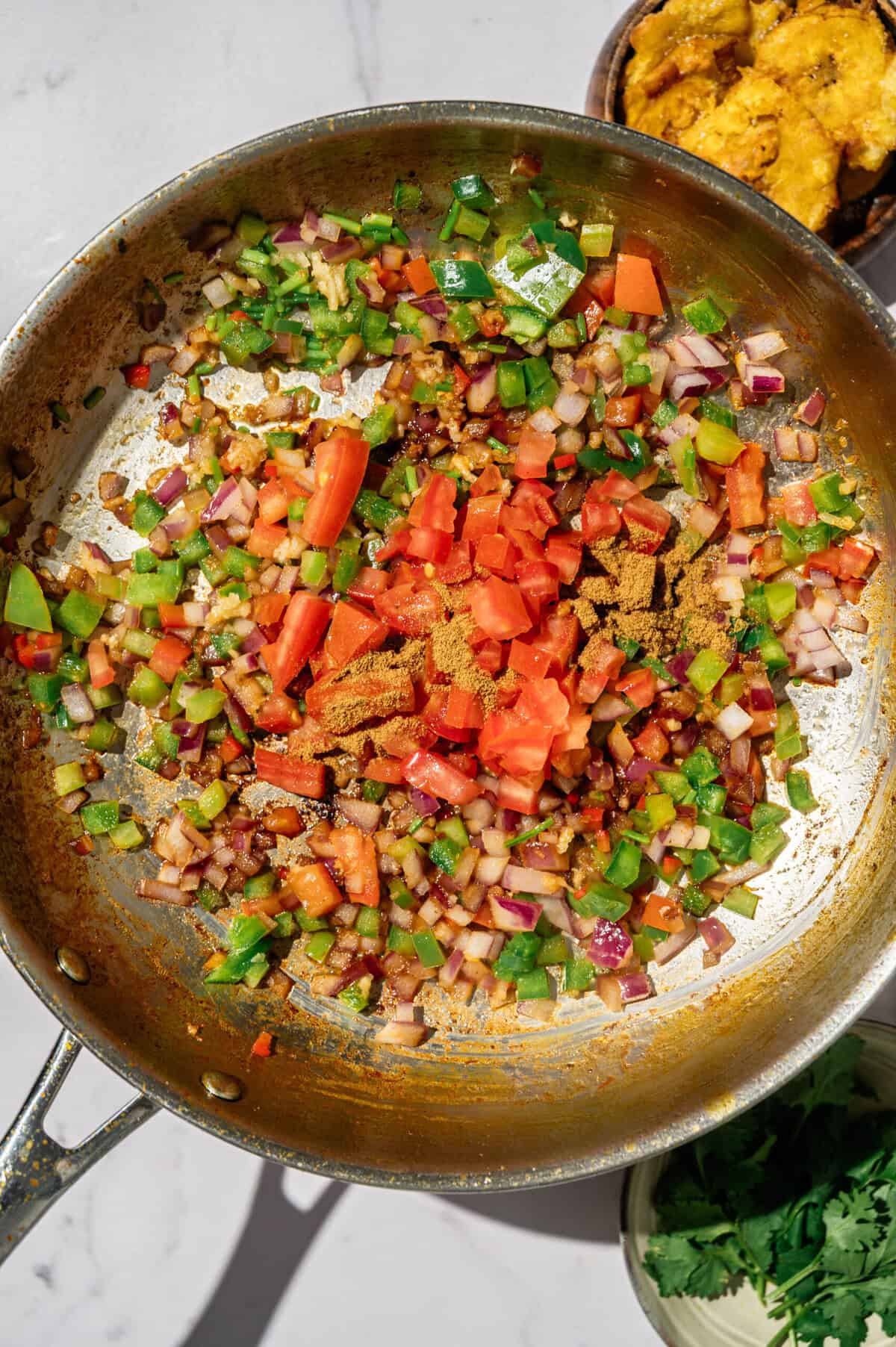 Diced tomato and ground cumin added to the refrito for encocado de camarón