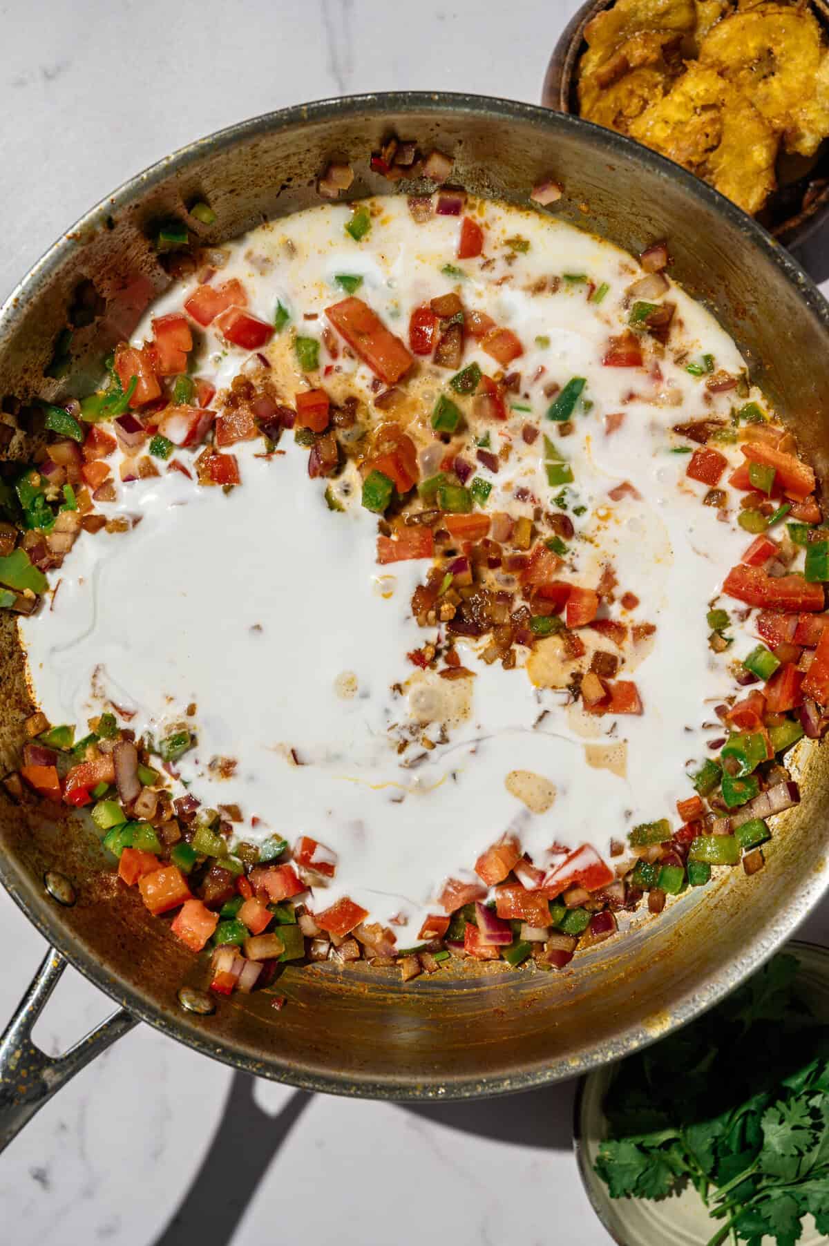 Pouring coconut milk into the skillet over the refrito