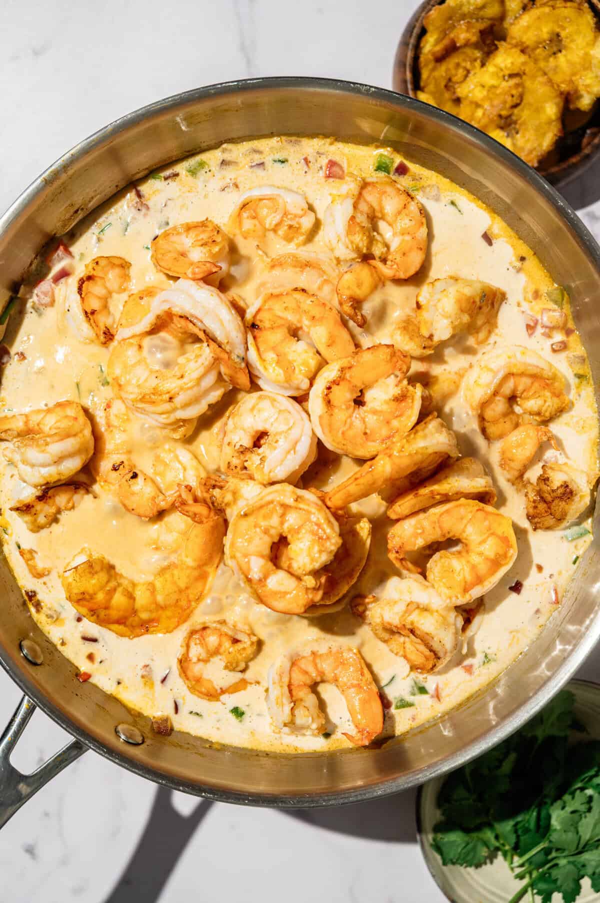 Seared shrimp returned to the creamy coconut milk sauce in the skillet