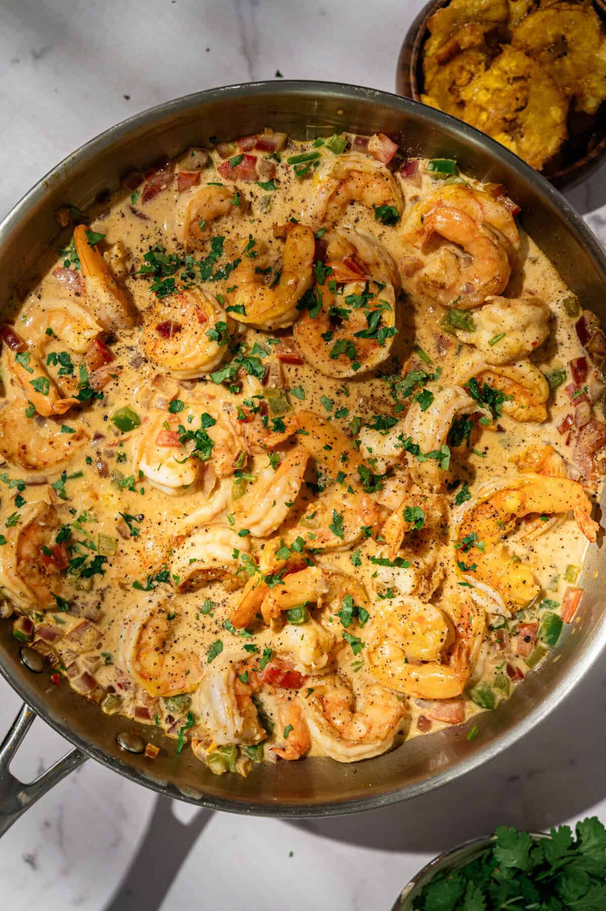 Encocado de camarón in a skillet garnished with fresh cilantro and black pepper