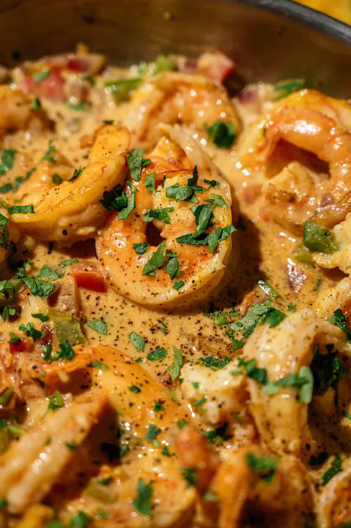 Close-up of a seared shrimp in creamy coconut milk sauce with cilantro and black pepper