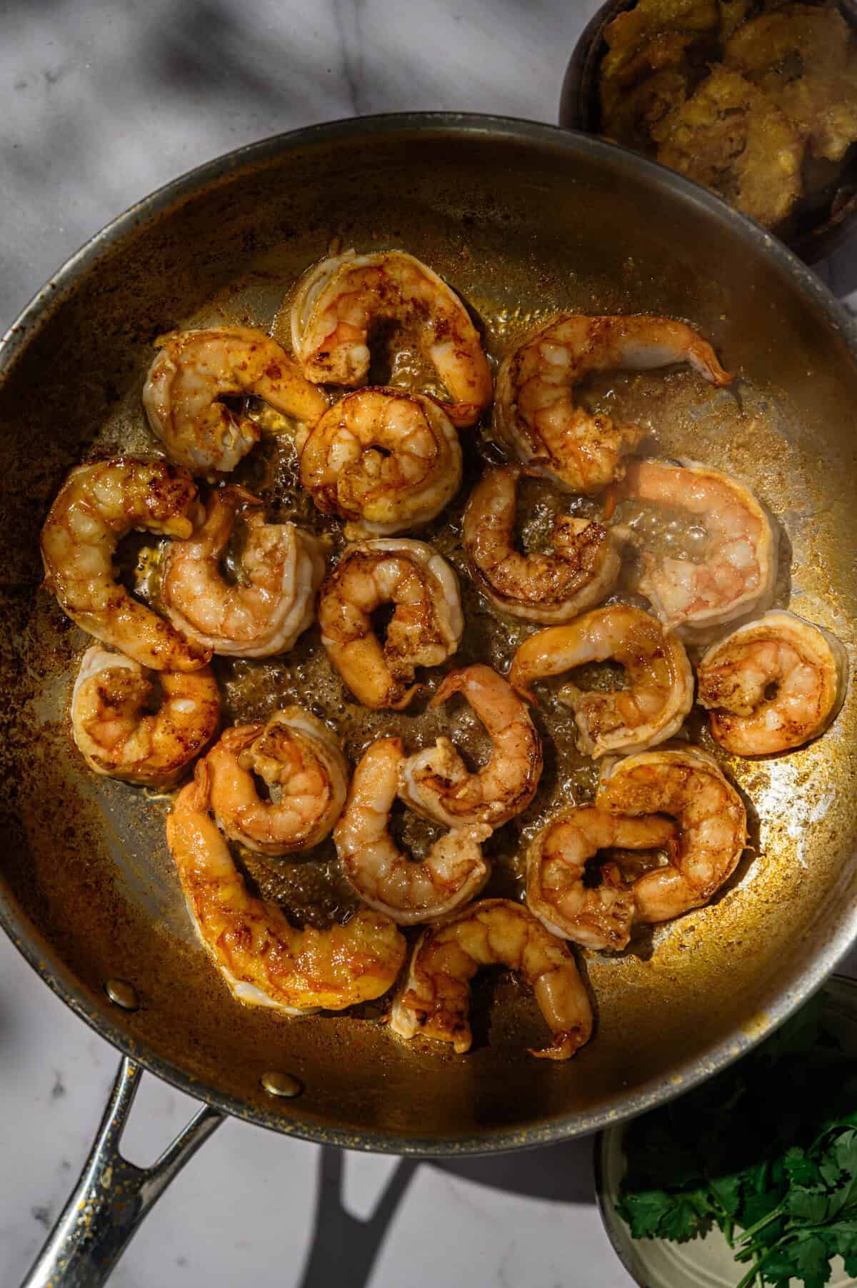 Seared shrimp flipped in a stainless steel skillet