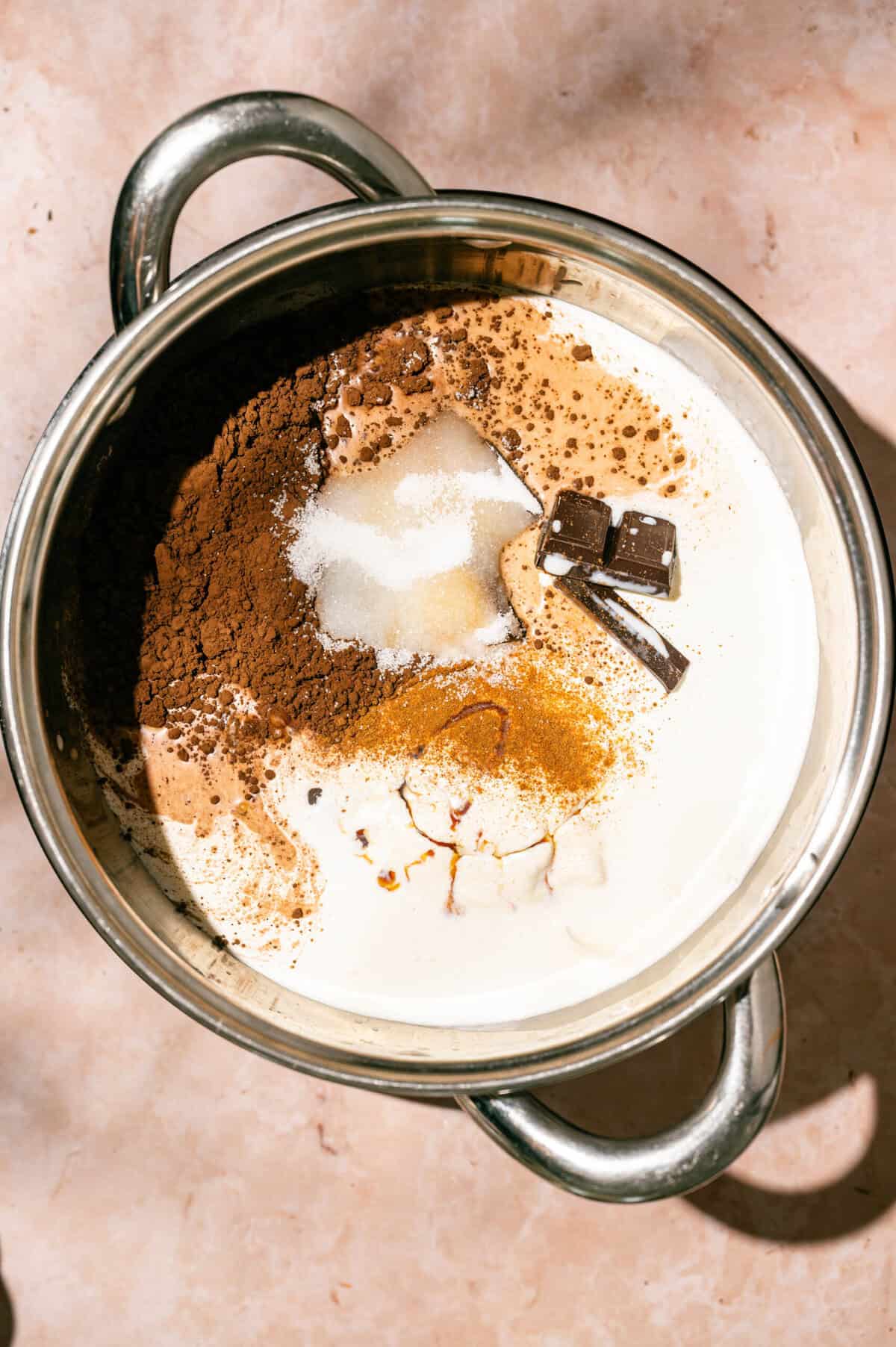 Milk, heavy cream, chocolate, cocoa powder, sugar, cinnamon, and vanilla in a saucepan for an easy hot chocolate recipe.