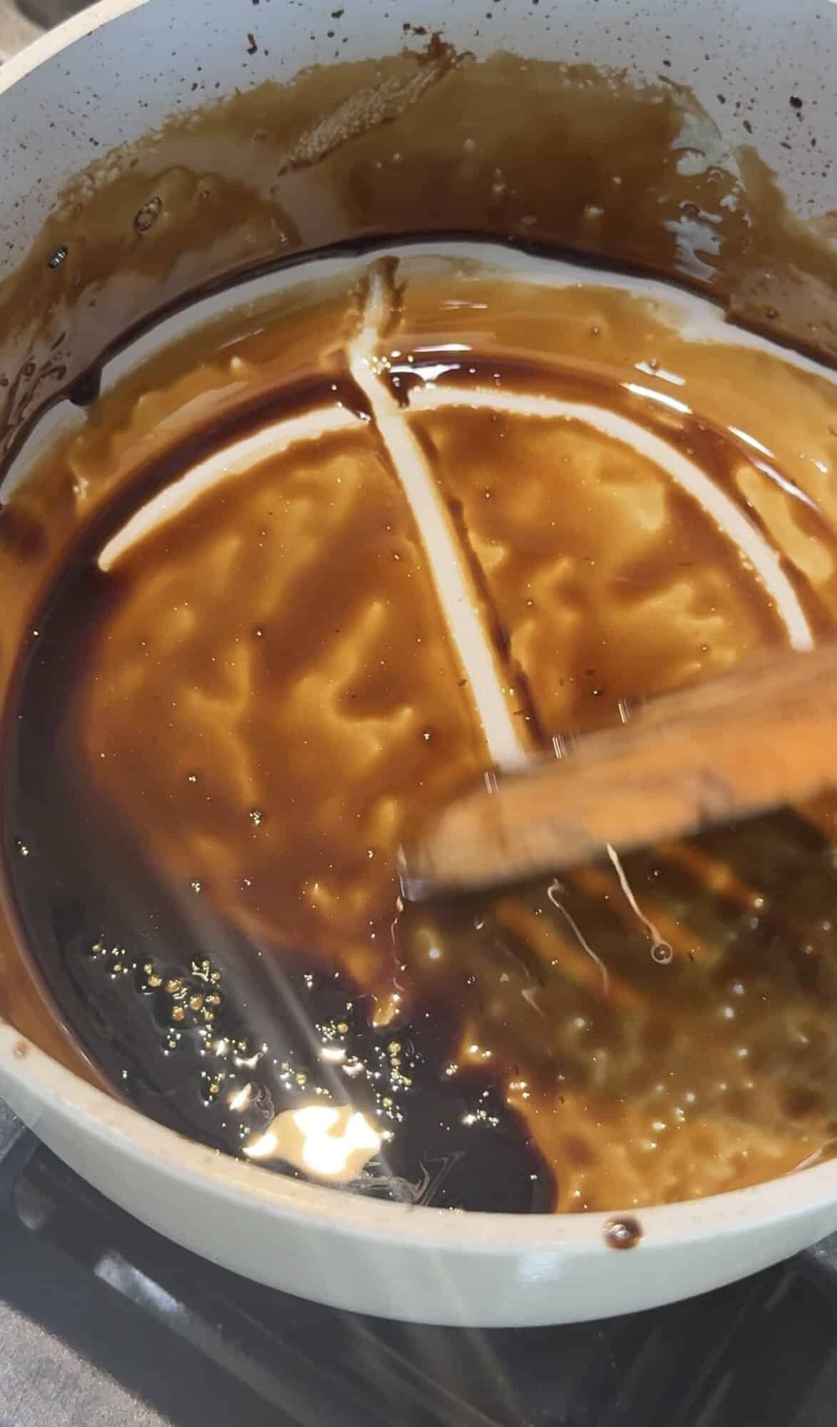 Reduced balsamic glaze in a saucepan, with spatula lines holding their shape to show it’s thick enough