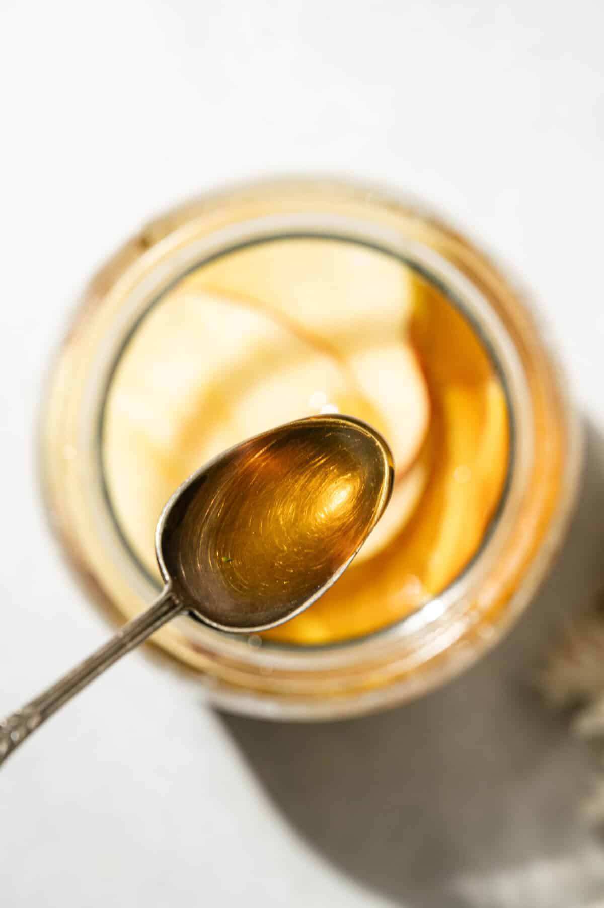 Spoonful of honey held over a jar of apple cider sangria to sweeten the fall sangria